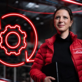 Mitarbeiterin von Linde Material Handling in einer Lagerhalle mit rotem leuchtenden Symbol eines Zahnrads im Hintergrund.