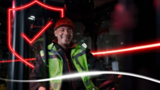 Person mit Arbeitskleidung und Schutzhelm sitz in einem Linde Stapler Person mit Arbeitskleidung und Schutzhelm sitz in einem Linde Stapler