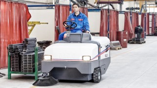 Mann fährt mit Reinigungsmaschine von Dulevo durch eine Produktionshalle